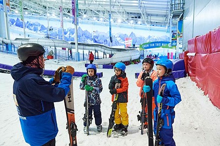 Group of children in ski gear listening to their instructor at Chill Factor<sup>e</sup>