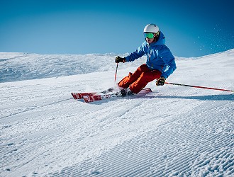 Man skiing on-piste with a blue sky background