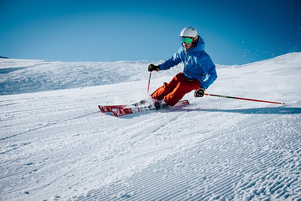 Man skiing on-piste with a blue sky background