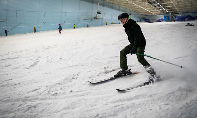 Chill Factor<sup>e</sup> customer in black winter clothing parallel skiing down indoor ski slope